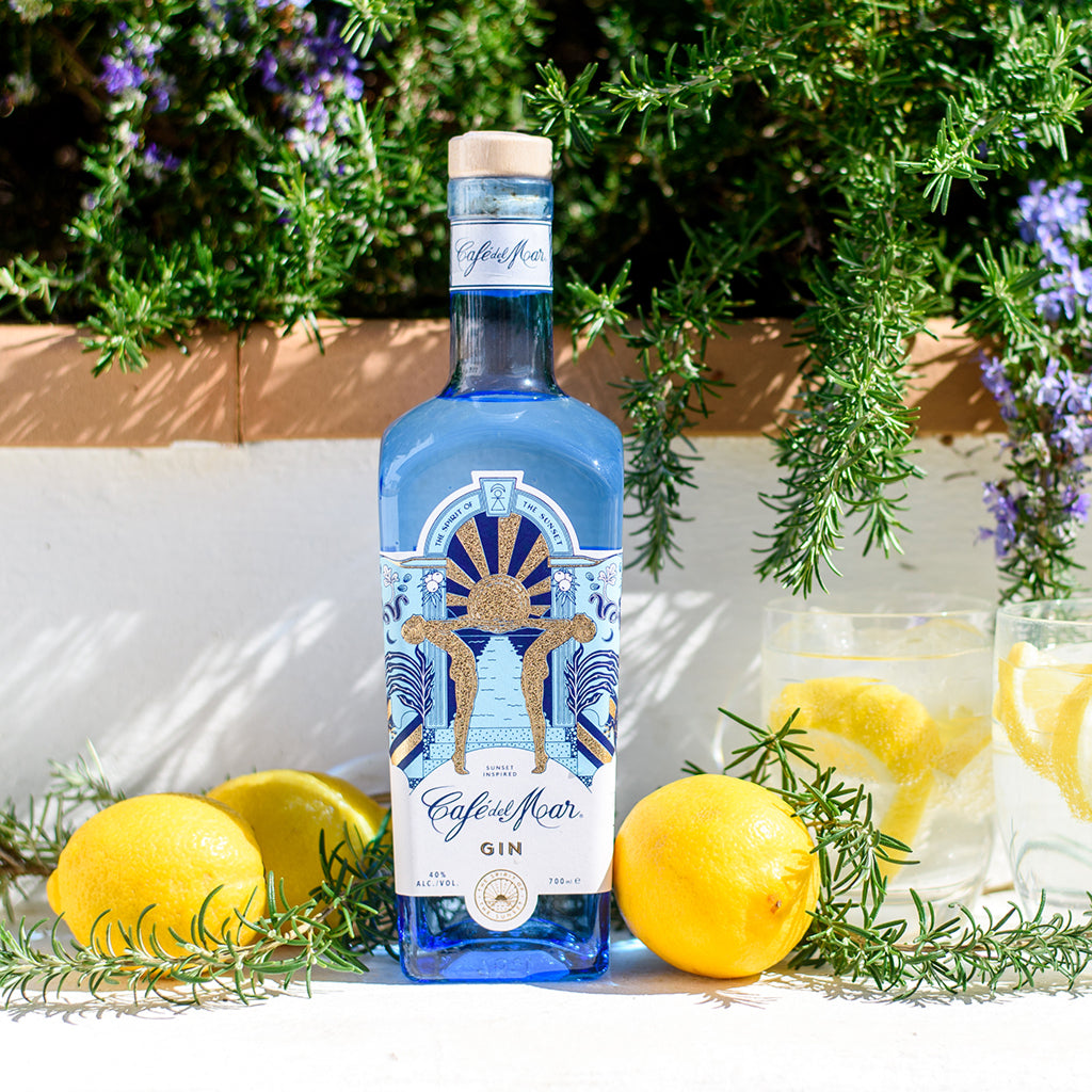 A bottle of Café del Mar Gin surrounded by thyme and lemonst